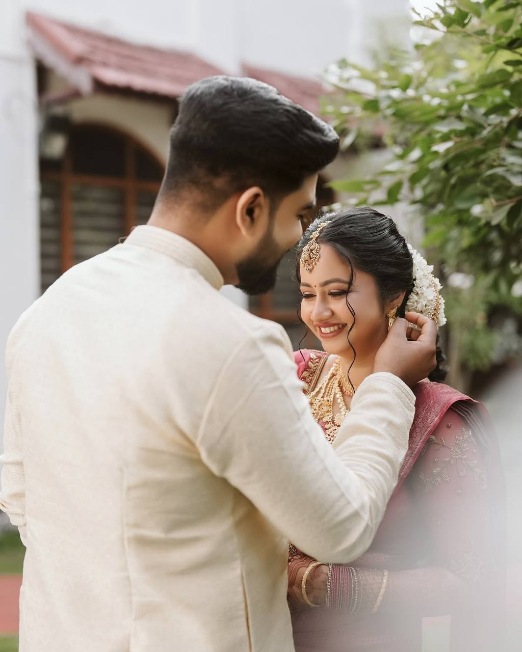 Kerala groom gently adjusting his bride's hair